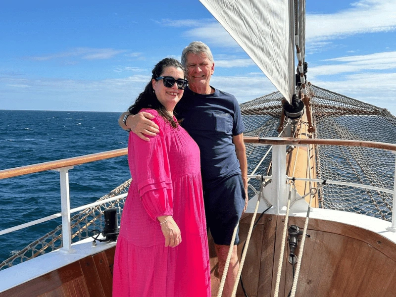 Anita and her husband Derek standing beneath a sail aboard Sea Cloud Spirit