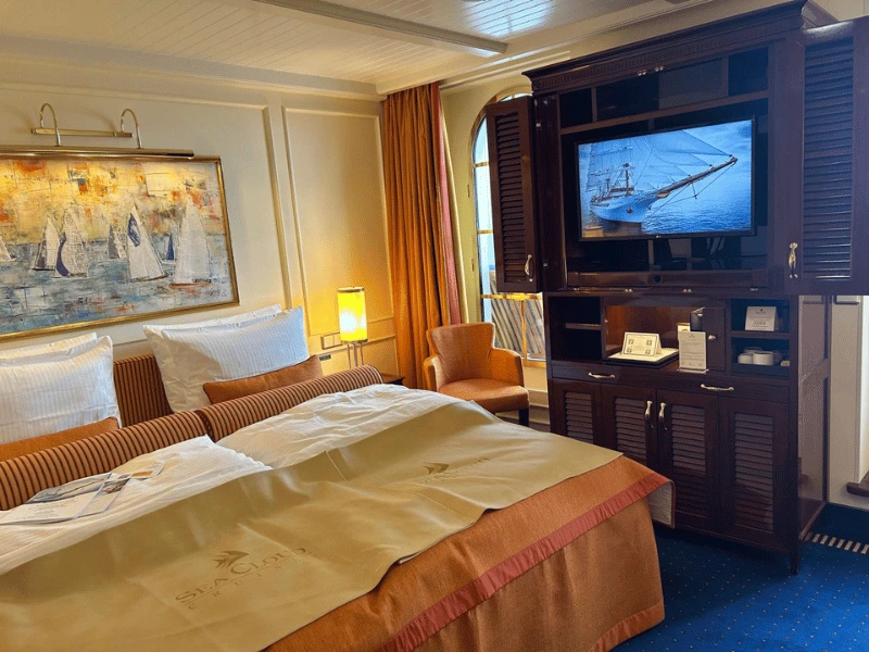 Junior suite aboard Sea Cloud Spirit with double bed, seating area and dark wood cabinetry
