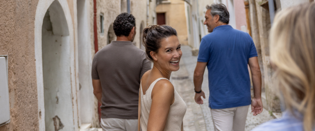 Four people happily walking through old street. One woman has turned around and is smiling.