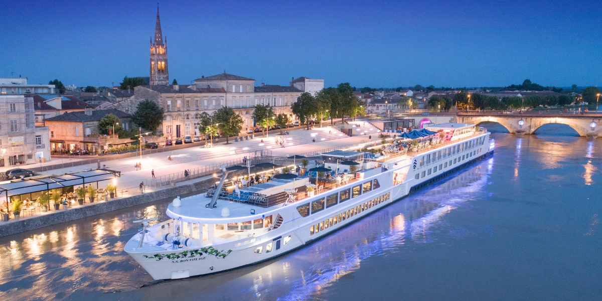 Uniworld Boutique River Cruises ship sailing through Bordeaux at dusk
