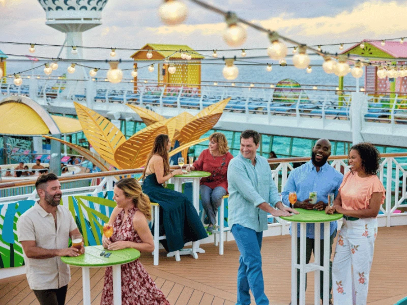 Guests enjoying drinks together at a colourful cruise ship deck bar