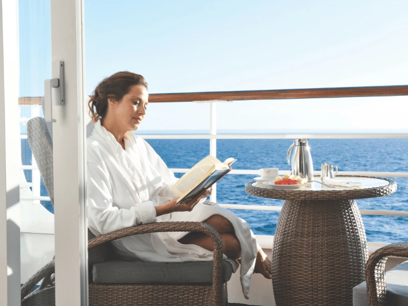 Guest reading on the private balcony of an Oceania Cruises Penthouse Suite
