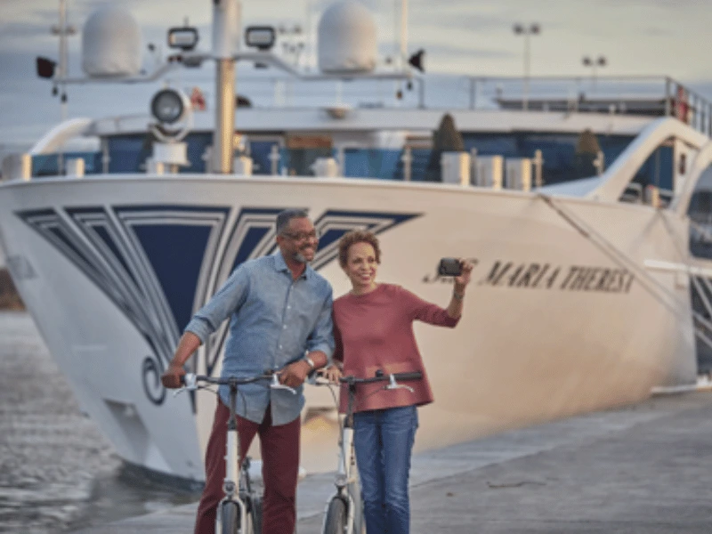 Couple with bicycles beside a river cruise ship