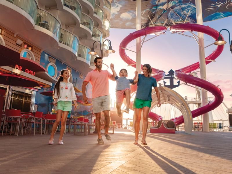 Family walking beneath the Ultimate Abyss slides aboard a Royal Caribbean cruise ship