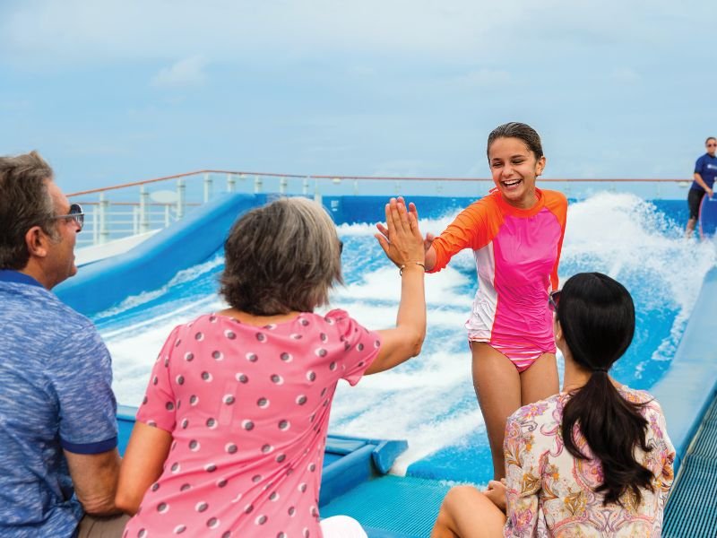 Young guest high-fiving her family after riding Royal Caribbean’s FlowRider surf simulator