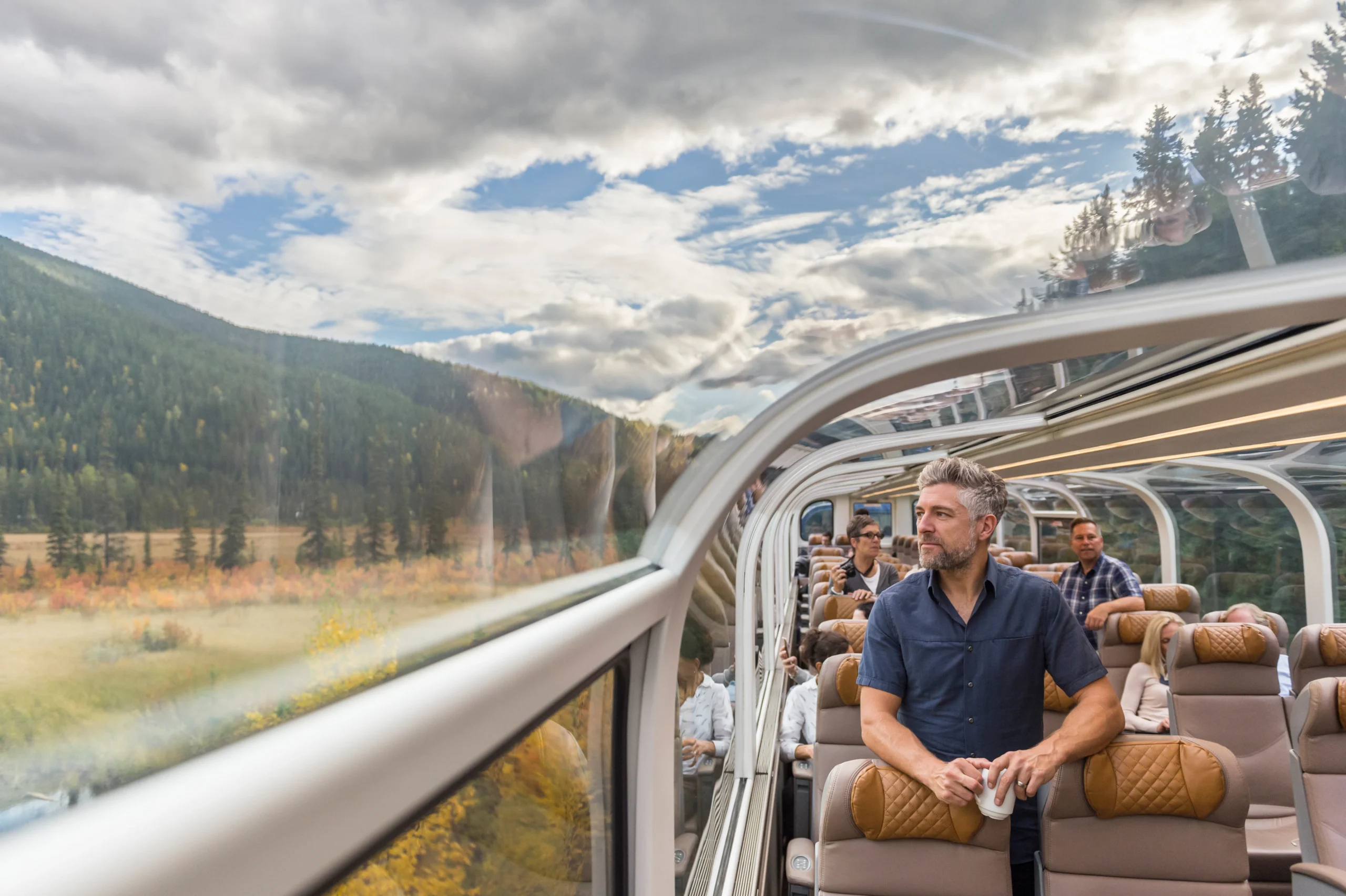 Guests enjoying mountain views inside a Rocky Mountaineer glass-dome carriage