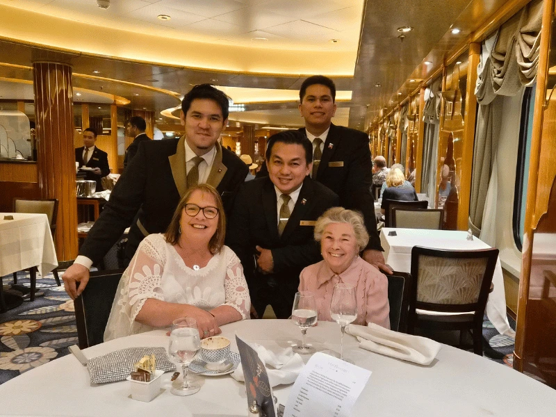 Sarah dining aboard Queen Elizabeth with members of the Cunard restaurant team