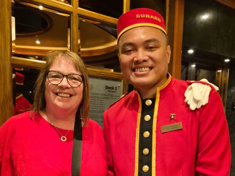 Sarah with a Cunard bellboy in traditional red uniform aboard Queen Elizabeth