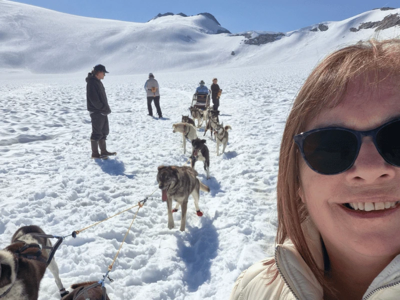 Sarah with a team of sled dogs on a snow-covered glacier in Alaska
