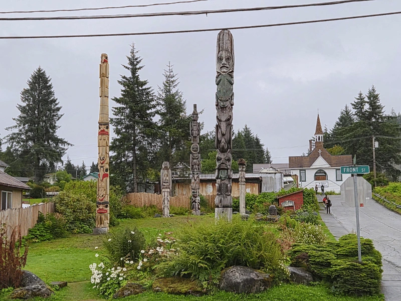 Traditional carved totem poles surrounded by trees in Wrangell, Alaska